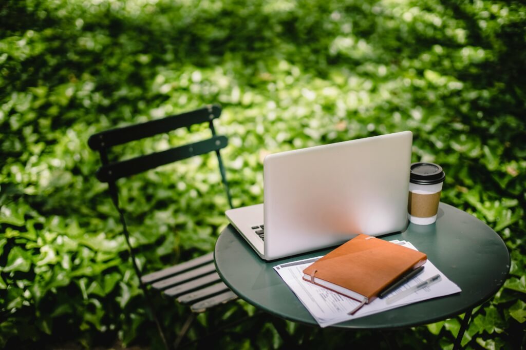 laptop on atable in the garden with a book and pencil